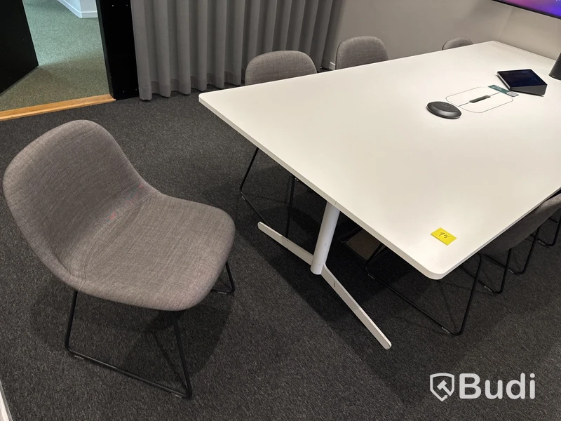 Konferensrum med bord, stolar, skärm och konferensutrustning