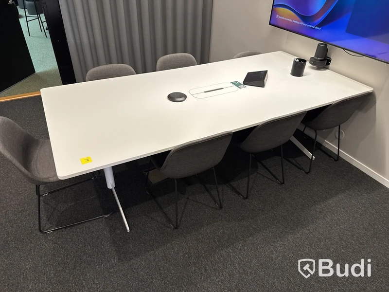 Konferensrum med bord, stolar, skärm och konferensutrustning