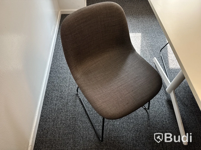 Konferensrum med bord, stolar, skärm och konferensutrustning