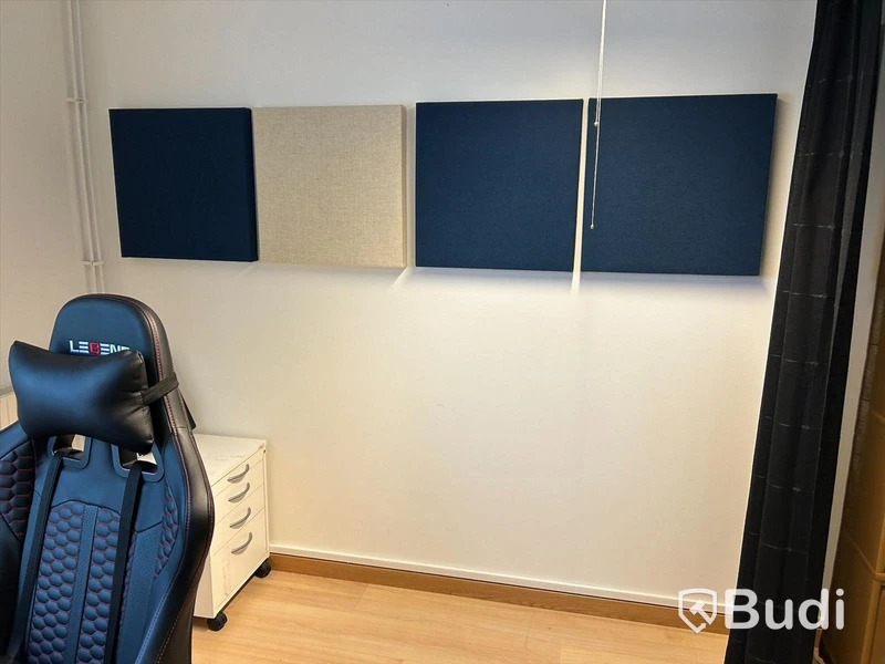 Kontorsrum med skrivbord, stol, datorskärm, besöksstolar med litet bord, ljudabsorbenter