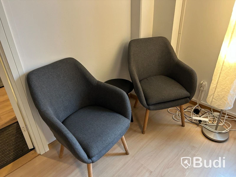 Kontorsrum med skrivbord, stol, datorskärm, besöksstolar med litet bord, ljudabsorbenter