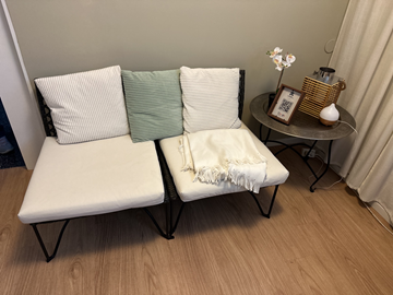 Soffa i rotting bredd 2x 65 cm, sitthöjd 35 cm med dynor. Runt bord i metall,  lykta mm.