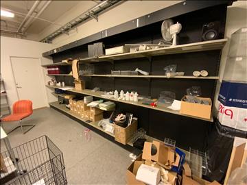 18st sektioner butiksinredning, hyllor utmed vägg, både vinklade hyllplan för böcker samt raka för diverse varor.