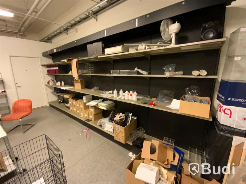 18st sektioner butiksinredning, hyllor utmed vägg, både vinklade hyllplan för böcker samt raka för diverse varor.