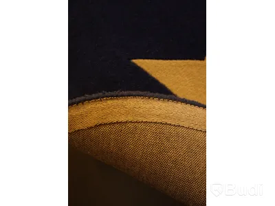 Handtuftad matta i en mörkblå färg med en vit stjärna i mitten.  Denna runda matta har en diameter på ca 88 cm.