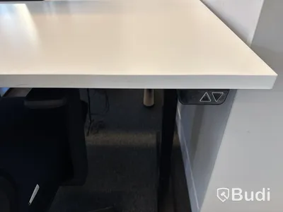 Höj- och sänkbart skrivbord med kontorsstol och datorskärm