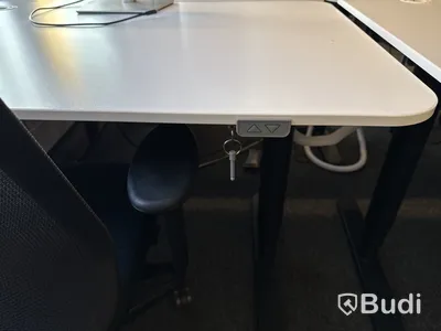 Höj- och sänkbart skrivbord med kontorsstol och datorskärm