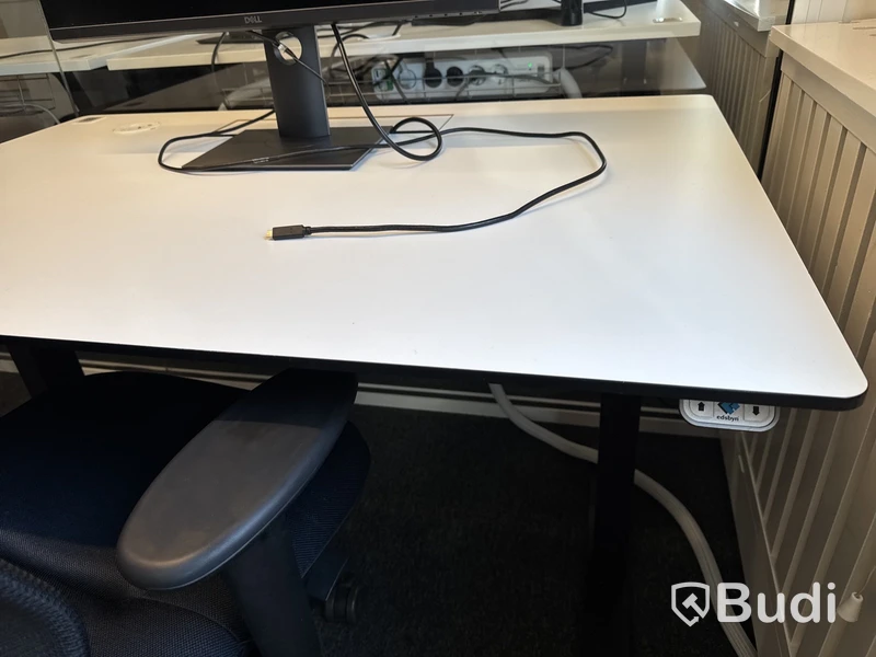 Höj- och sänkbart skrivbord med kontorsstol och datorskärm