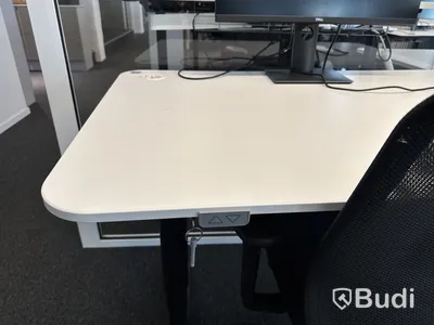 Höj- och sänkbart skrivbord med kontorsstol och datorskärm