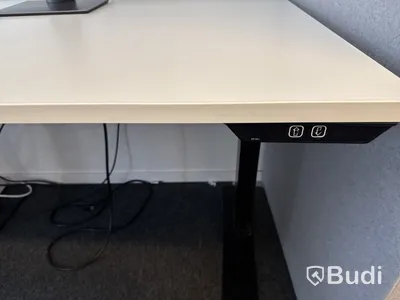 Höj- och sänkbart skrivbord med kontorsstol och datorskärm