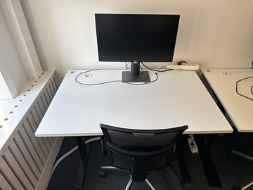 Höj- och sänkbart skrivbord med kontorsstol och datorskärm