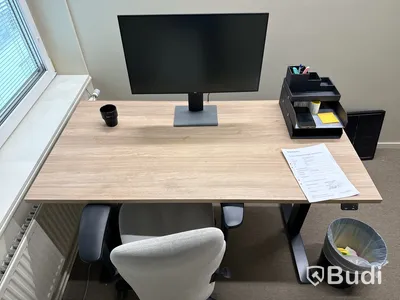 Höj- och sänkbart skrivbord med kontorsstol och datorskärm