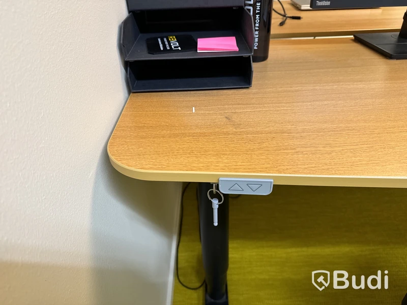 Höj- och sänkbart skrivbord med kontorsstol, datorskärm och bordslampa