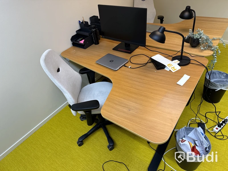 Höj- och sänkbart skrivbord med kontorsstol, datorskärm och bordslampa