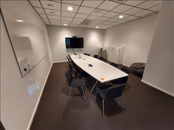 Konferensrum med bord, stolar, tv skärm 