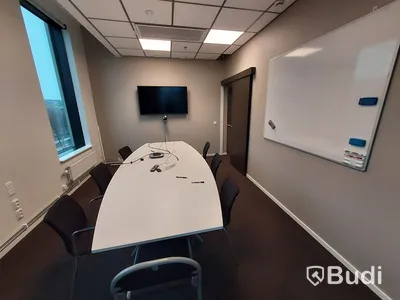 Konferensrum med tv-skärm, samt kamera/högtalare, bord och stolar
