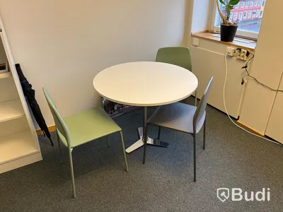 Kontorsrum, vitt skrivbord, stol, vitt skåp, besöksstolar med bord, soffa
