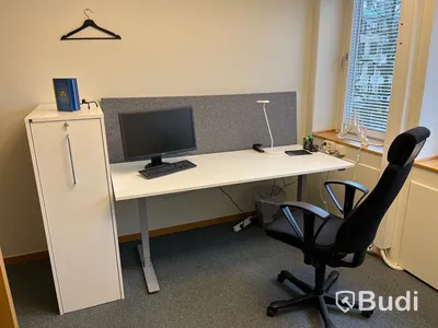 Kontorsrum, vitt skrivbord, stol, vitt skåp, besöksstolar med bord, dragskjutskåp