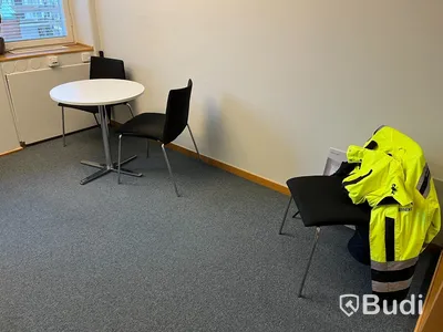 Kontorsrum, vitt skrivbord, stol, vitt skåp, besöksstolar med bord, dragskjutskåp