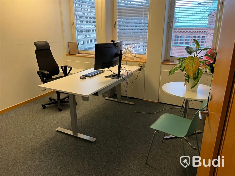 Kontorsarbetsplats, höj- & sänkbart skrivbord, stol, datorskärm, bokhylla, besöksbord med stolar