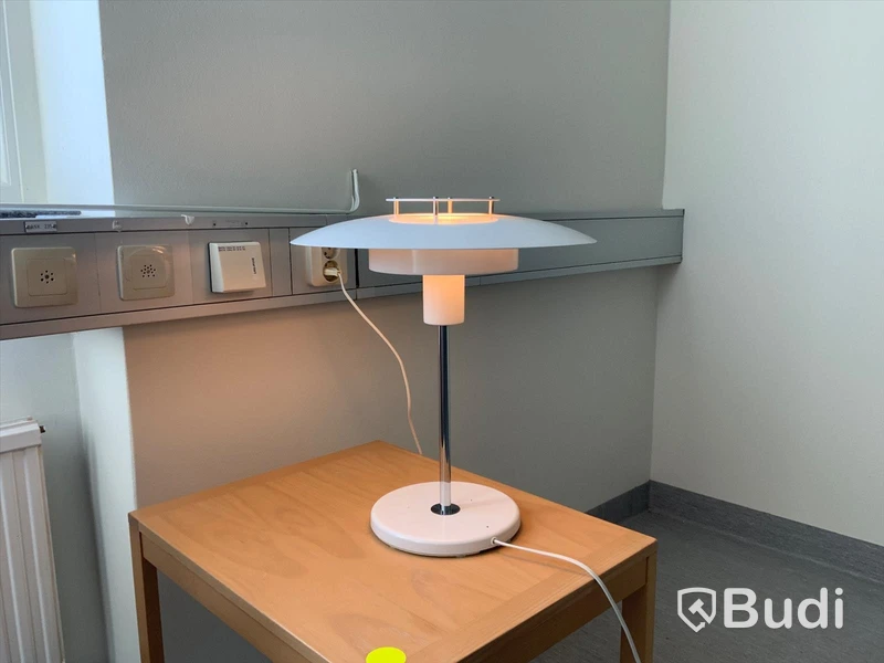 Lampa i vit plåt på gjutjärnsfot.