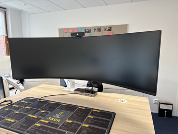 Samsung 49 tum curved datorskärm med bordfäste USB-docka samt logitech kamera. Skärmen är C49G95TSSR