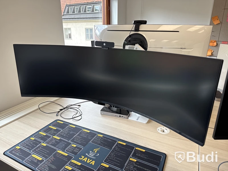 Samsung 49 tum curved datorskärm med bordfäste USB-docka samt logitech kamera. Skärmen är C49G95TSSR