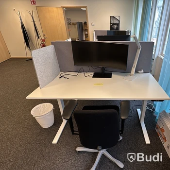 Kontorsplats med höj- och sänkbart skrivbord, kontorsstol och Samsung-skärm