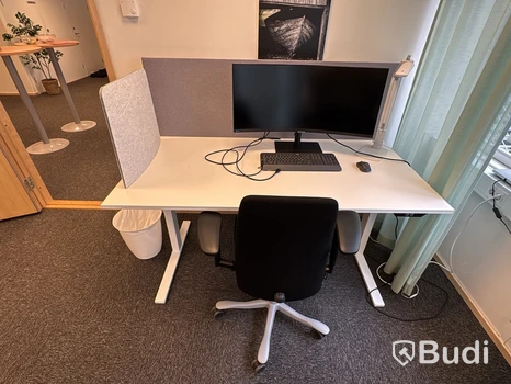 Höj- och sänkbart skrivbord med kontorsstol och Samsung-skärm