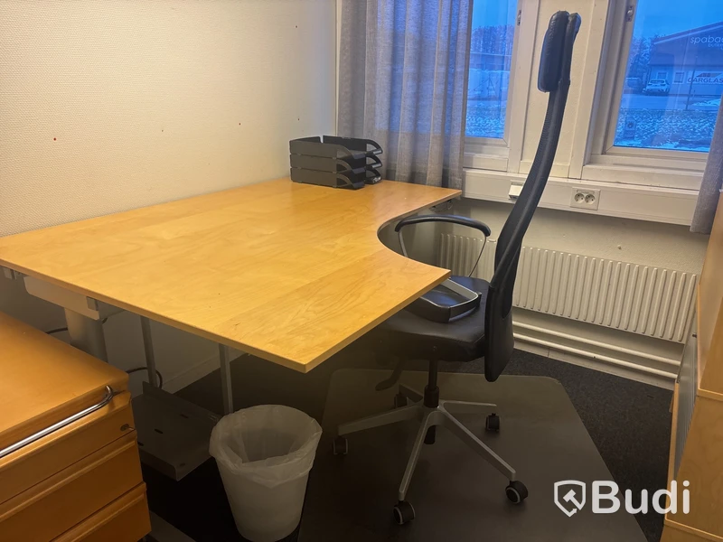 Kontorsplats med skrivbord, stol och skåp.