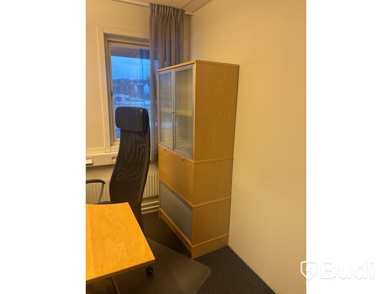Kontorsplats med skrivbord, stol och skåp.