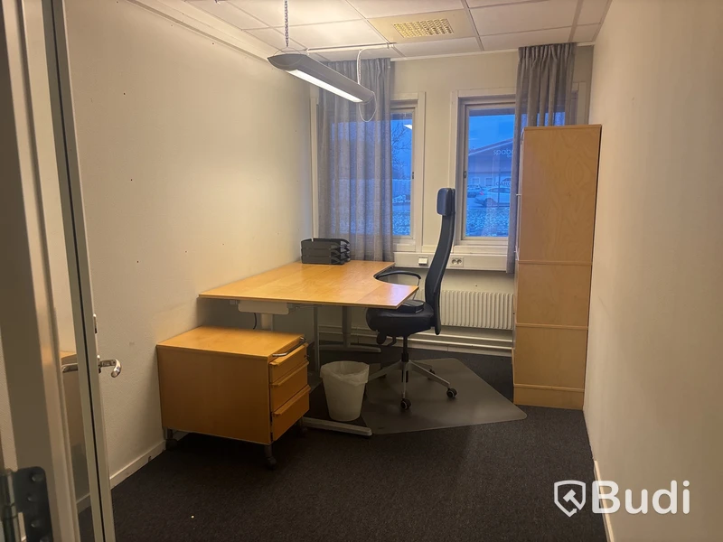 Kontorsplats med skrivbord, stol och skåp.