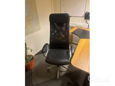 Kontorsplats med skrivbord, stol och hylla.