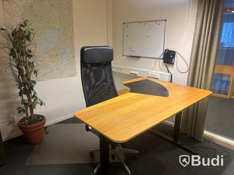 Kontorsplats med skrivbord, stol och hylla.