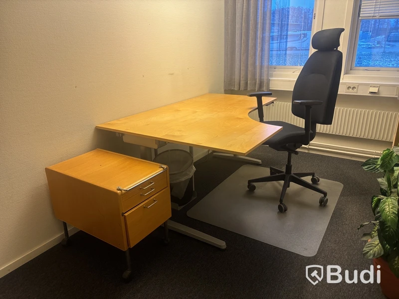 Kontorsplats med skrivbord, stol och skåp.