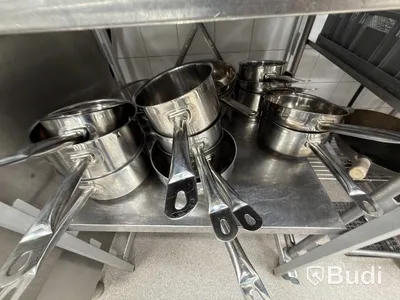 Two stainless steel shelves with assorted stainless steel kitchen accessories and oven drawers