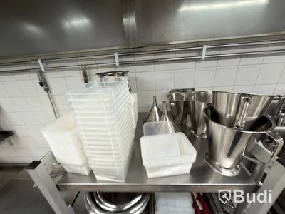 Two stainless steel shelves with assorted stainless steel kitchen accessories and oven drawers