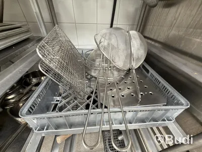 Two stainless steel shelves with assorted stainless steel kitchen accessories and oven drawers