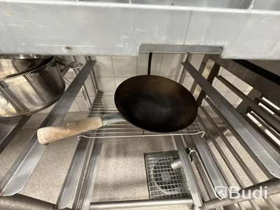 Two stainless steel shelves with assorted stainless steel kitchen accessories and oven drawers