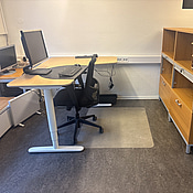 Kontorsplats med skrivbord, stol och skåp.