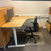 Kontorsplats med skrivbord, stol och skåp.