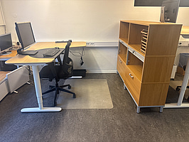 Kontorsplats med skrivbord, stol och skåp.