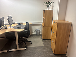 Kontorsplats med skrivbord, stol och skåp.