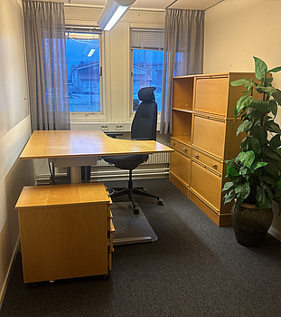 Kontorsplats med skrivbord, stol och skåp.