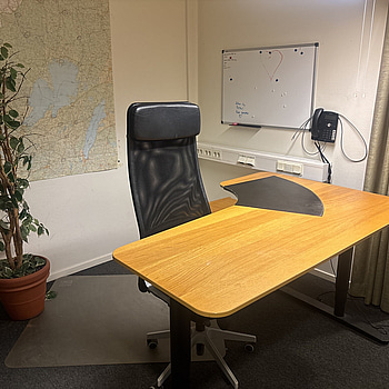 Kontorsplats med skrivbord, stol och hylla.