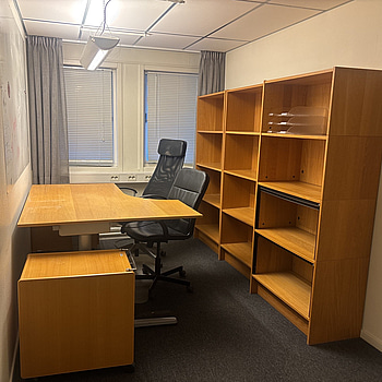 Kontorsplats med skrivbord, stol och skåp.