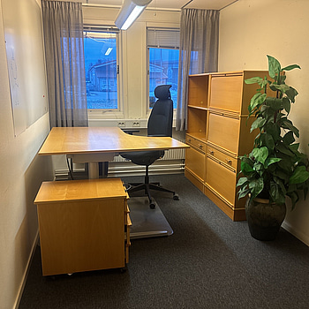 Kontorsplats med skrivbord, stol och skåp.