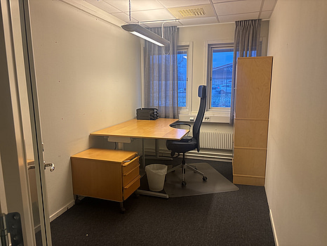 Kontorsplats med skrivbord, stol och skåp.