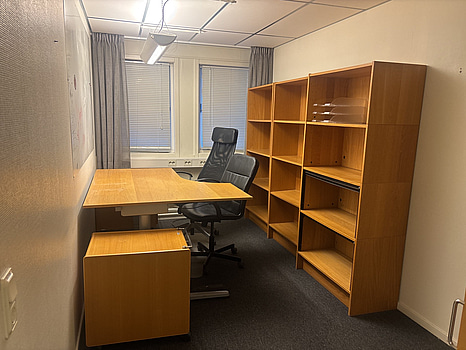 Kontorsplats med skrivbord, stol och skåp.