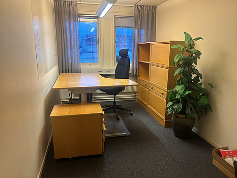 Kontorsplats med skrivbord, stol och skåp.